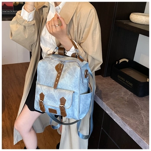 Detailed view of light blue retro canvas backpack with brown leather trim and metal buckles