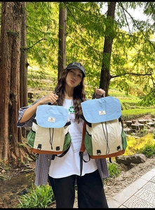 Outdoor view of two contrast color canvas backpacks with drawstring and buckle closure