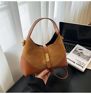 Detail of a brown suede and leather patchwork dumpling bag with a gold metal buckle