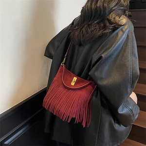 Detail of red tassel shoulder bag showing the vintage fringe texture and gold lock