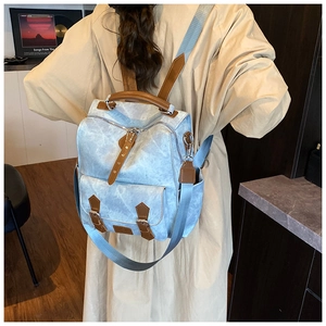 Detailed back view of a light blue vintage backpack with brown leather straps and multi-pockets
