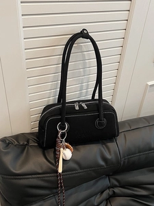 Retro black canvas Boston bag with contrast white stitching and baseball charms on a sofa