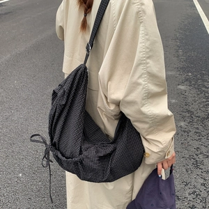 Side view of checkered canvas crossbody bag featuring adjustable strap and drawstring detail
