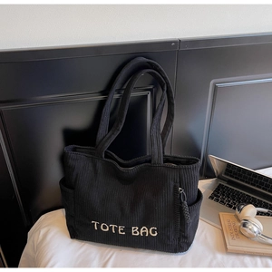 Détail du sac fourre-tout en velours côtelé noir avec broderie et poche zippée latérale