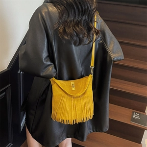 Detailed view of yellow suede crossbody bag with long tassels and metal twist lock closure