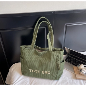 Détail du sac cabas en velours côtelé vert avec broderie blanche et poches latérales