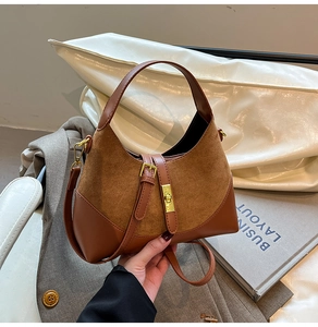 Close-up of suede contrast handbag showing gold buckle and adjustable strap detail