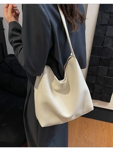 Minimalist beige pebble leather tote bag shown on model in a professional suit