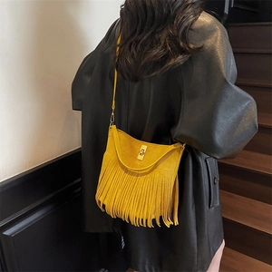 Detail of yellow fringe crossbody bag with gold metal clasp on a black leather coat