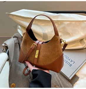 Detail of contrast leather handbag featuring golden metal buckle and top handle