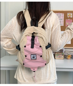 Rear view of model wearing a pink and beige color-block nylon backpack with penguin patch