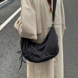 Detail view of black plaid crossbody bag with side drawstring and crescent moon shape