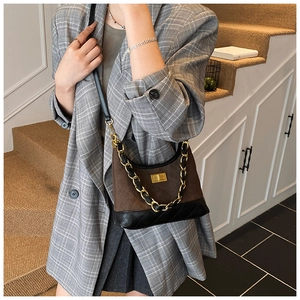 Close-up of quilted pattern and gold twist lock on the brown suede shoulder bag