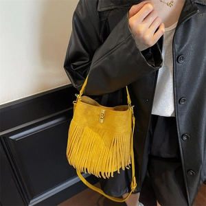 Detailed close-up of yellow tassel bucket bag with golden metal swivel clasp and matte texture