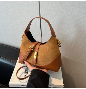 Close-up of brown suede and leather contrast handbag with elegant metal buckles