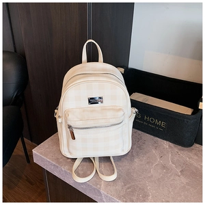 Détail d'un sac à dos à carreaux crème avec poche zippée et plaque logo en métal
