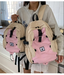 Detail view of two beige and pink colorblock nylon backpacks with cross bungee cords
