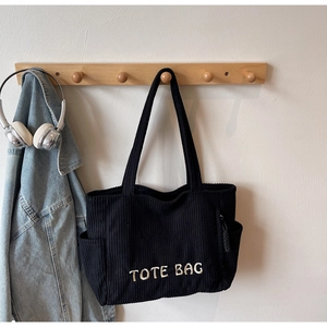 Détail du sac cabas noir en velours côtelé avec broderie TOTE BAG sur un crochet