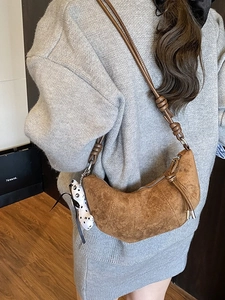 Borsa a mezzaluna in pelle opaca marrone con tracolla annodata e ciondolo panda su modella