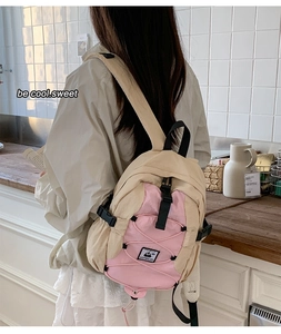 Detail of a beige and pink nylon backpack featuring an elastic drawstring system