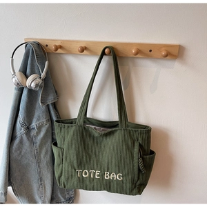 Détail du sac fourre-tout en velours côtelé vert foncé avec broderie et poche latérale utile