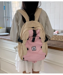 Detail view of the beige and pink backpack showing elastic cords and side buckles