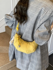 Borsa a mezzaluna gialla chic con tracolla annodata e ciondolo su blazer grigio