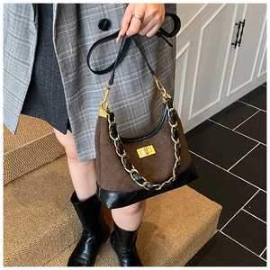 Brown and black quilted suede hobo bag with gold chain strap shown on model in studio