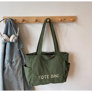 Détail du sac cabas en velours côtelé vert forêt avec broderie blanche et poche latérale