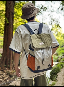 Detail of color-block nylon backpack featuring drawstring closure and flap with buckle