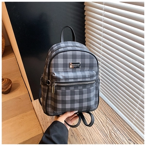 Détail du mini sac à dos à carreaux gris avec bordure en cuir et plaque logo métal