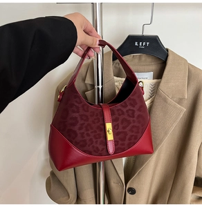 Detail of burgundy leather handbag with leopard print panel and golden twist lock closure