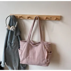 Détail d'un sac fourre-tout en velours rose avec broderie TOTE BAG et poches latérales pratiques