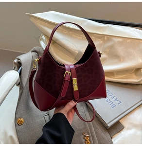 Close-up of burgundy leather bag with leopard print texture and golden buckle details