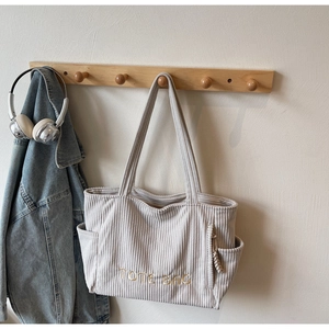Détail montrant la texture du velours côtelé et la broderie TOTE BAG sur le sac beige