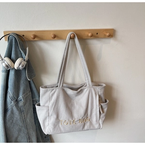 Détail du cabas en velours côtelé crème avec broderie TOTE BAG et poche latérale