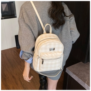 Vue détaillée du mini sac à dos à carreaux beige avec détails métalliques argentés