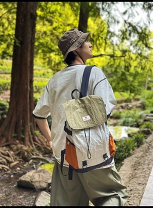 Detail of color-block backpack with wrinkled fabric and strap in forest setting