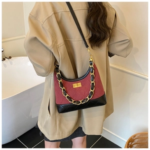 Quilted burgundy and black shoulder bag with gold chain strap shown on model's shoulder