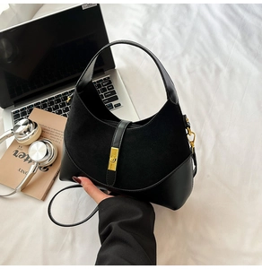 Detail of black contrast-textured hobo bag featuring a glossy gold clasp and matte finish