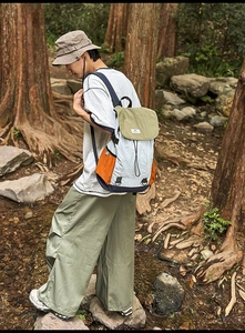 Detail of color-block hiking backpack with orange pocket in a forest setting