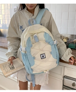 Detail of cream and blue lightweight backpack featuring a cute penguin patch and bungee cords