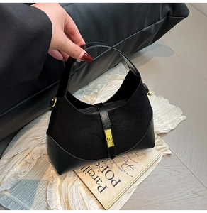 Detail of classic black contrast handbag featuring suede texture and gold buckle hardware