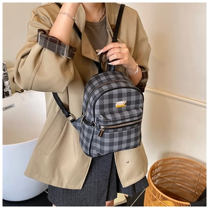 Détail d'un mini sac à dos à carreaux avec lanières en cuir et logo métallique doré