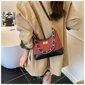Detail view of burgundy quilted suede shoulder bag with gold chain and metal hardware