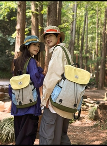 Close-up of color-block nylon backpack with drawstring and matching bucket hat in nature