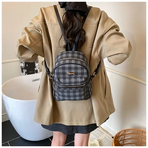 Gros plan d'un mini sac à dos à carreaux vintage sur un mannequin en intérieur