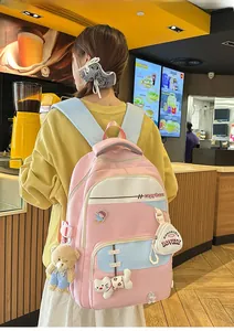Pink and blue school backpack featuring cute cartoon pins and a plush pendant accessory