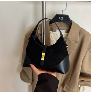 Close-up of black crescent bag with suede-leather splicing and gold metal clasp