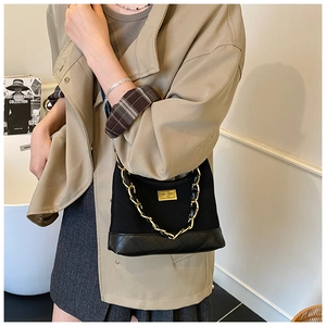 Macro detail of black quilted texture fabric and gold metal chain on shoulder bag
